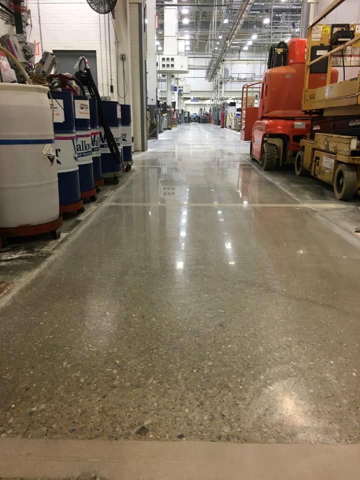 Image of industrial polished concrete floors with a glossy, reflective surface and intricate patterns, creating a sleek and modern look for the space.