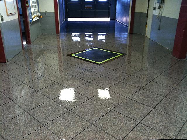 Image of an Epoxy Flake Tile flooring system in a showroom, featuring a glossy, reflective surface with a variety of colorful flakes embedded in a light gray base.